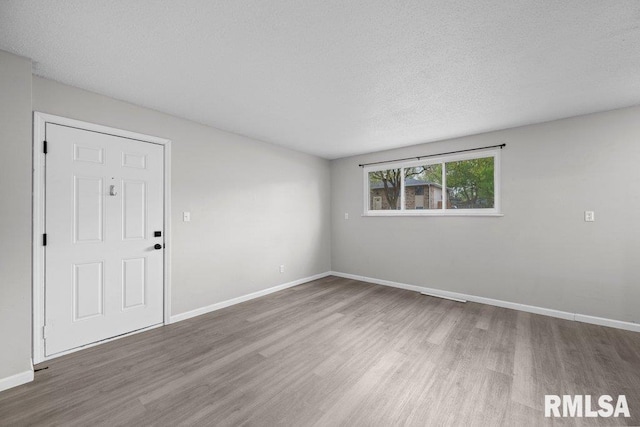 spare room featuring a textured ceiling, baseboards, and wood finished floors