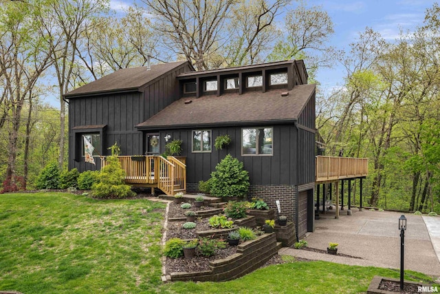 view of front facade featuring board and batten siding, driveway, a deck, roof with shingles, and a front lawn