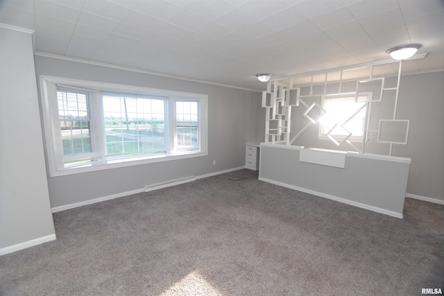 empty room featuring crown molding, baseboards, and carpet