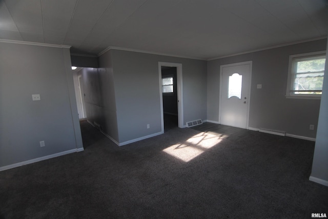 interior space featuring crown molding, a wealth of natural light, dark carpet, and visible vents