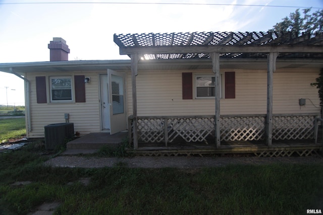 rear view of property featuring central air condition unit and a chimney