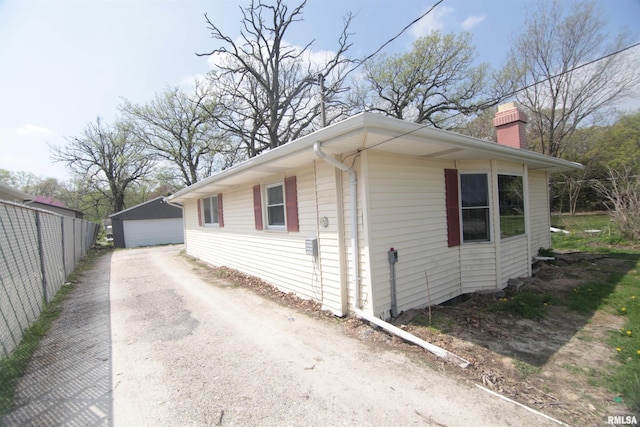 view of side of property featuring a detached garage, an outbuilding, and a chimney