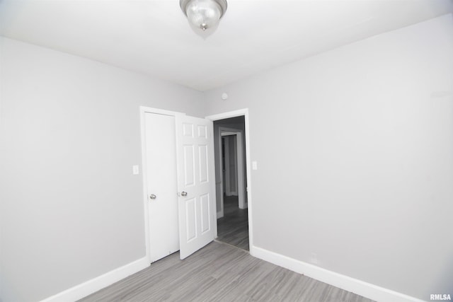 spare room featuring baseboards and light wood finished floors