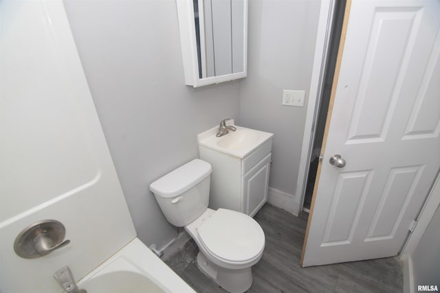 bathroom with a bathing tub, toilet, wood finished floors, and vanity