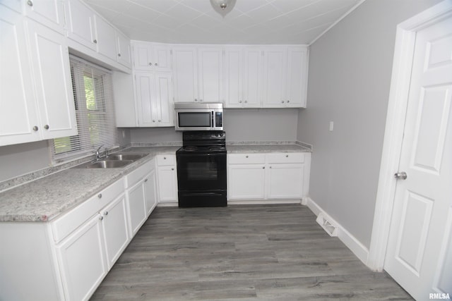 kitchen featuring white cabinetry, stainless steel microwave, a sink, and black / electric stove