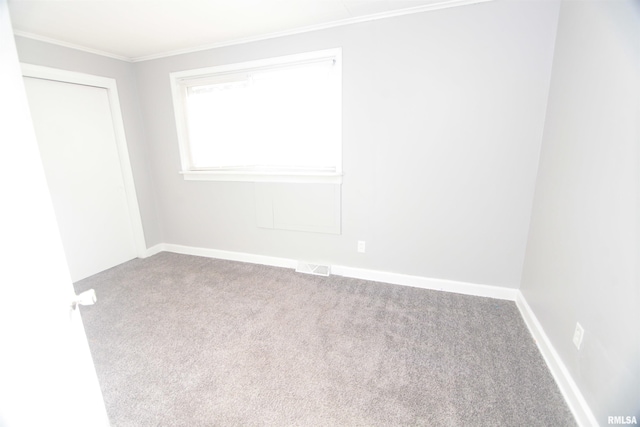 carpeted spare room with baseboards, visible vents, and ornamental molding