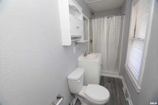 bathroom featuring a shower with shower curtain, wood finished floors, a healthy amount of sunlight, and toilet
