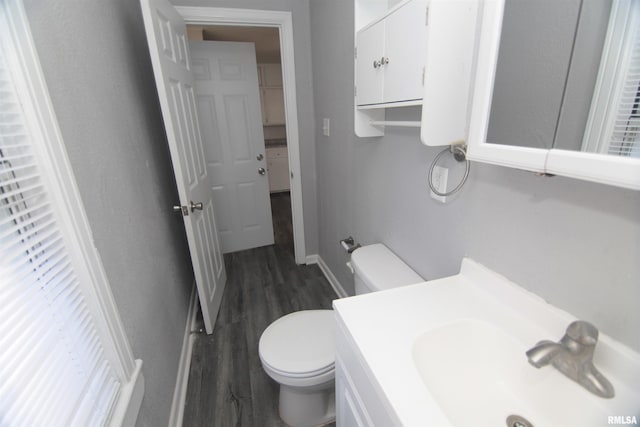 half bathroom with toilet, baseboards, wood finished floors, and vanity