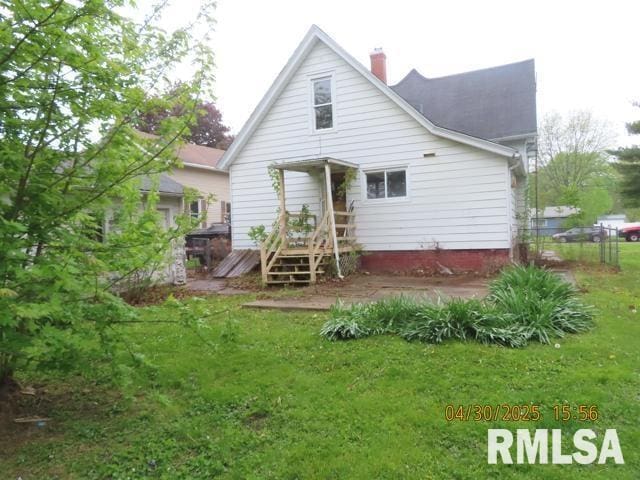 back of property with a chimney and a yard