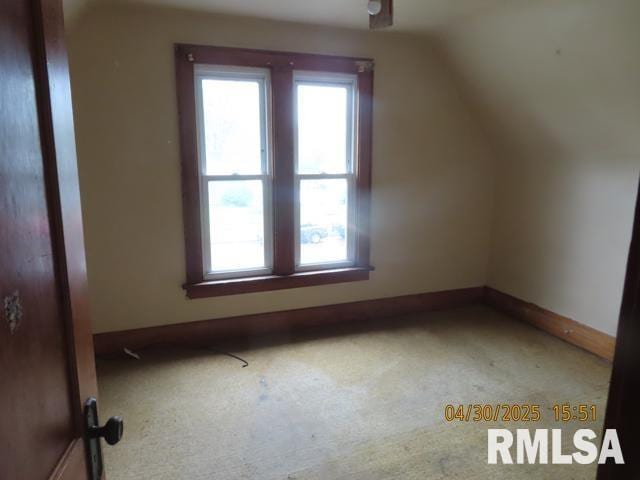 additional living space featuring carpet floors, baseboards, vaulted ceiling, and a healthy amount of sunlight