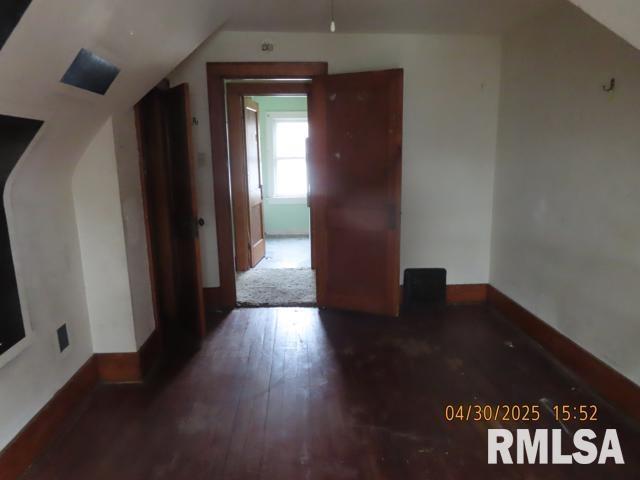 additional living space featuring baseboards, hardwood / wood-style floors, and lofted ceiling