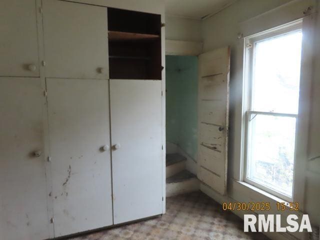 unfurnished bedroom featuring multiple windows, light floors, and a closet