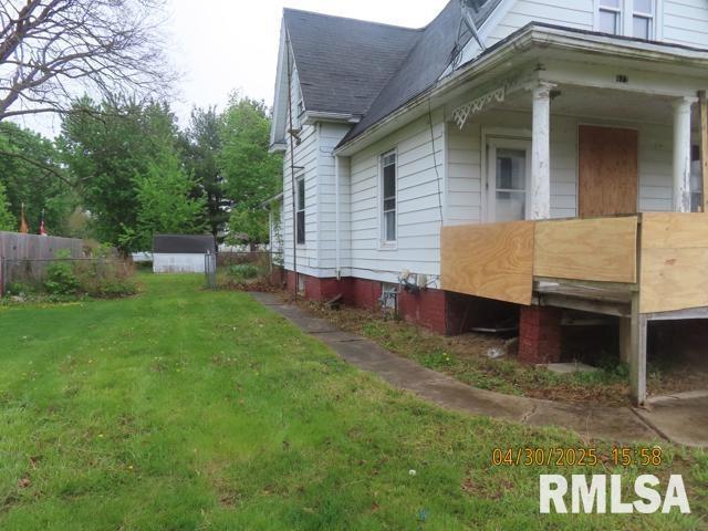 view of property exterior featuring a yard, fence, and a shingled roof