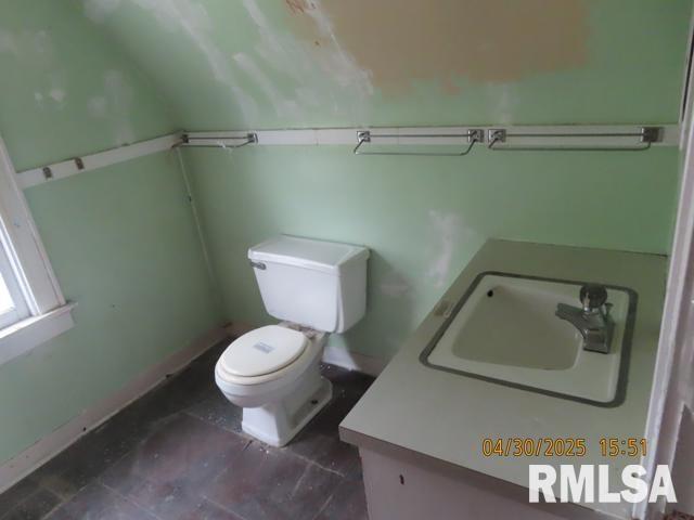 half bath featuring toilet, baseboards, and vanity