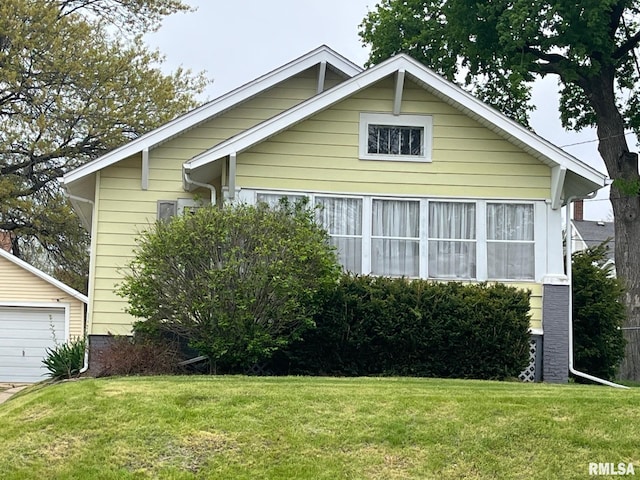 view of front of house featuring a garage, an outdoor structure, and a front lawn