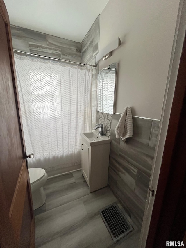 bathroom with visible vents, wood finished floors, shower / tub combo, vanity, and toilet