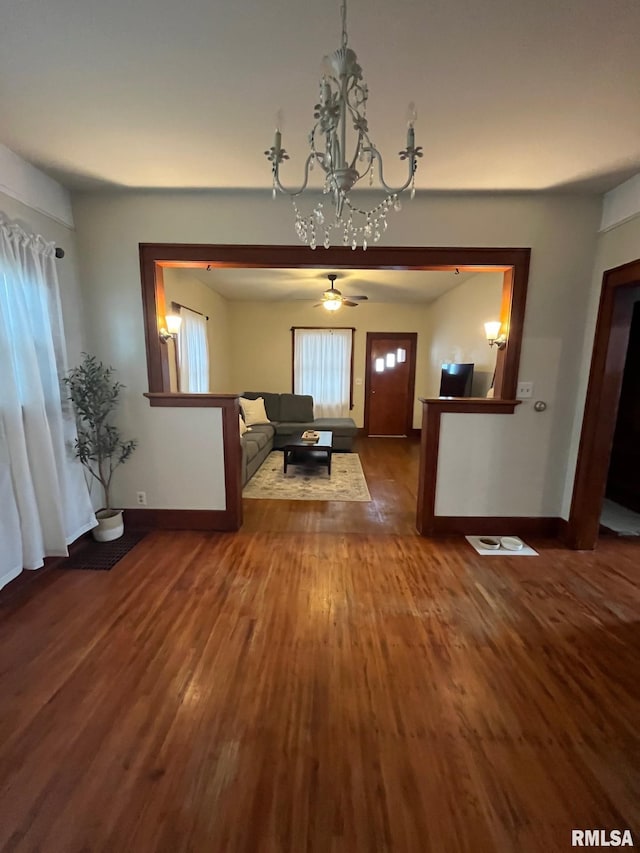 unfurnished living room featuring baseboards, wood finished floors, and ceiling fan with notable chandelier
