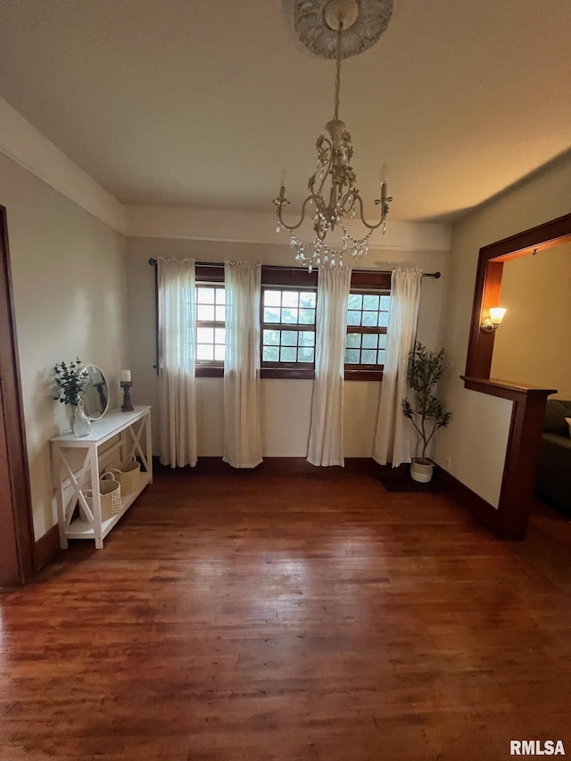 unfurnished dining area with an inviting chandelier, baseboards, dark wood-style flooring, and a healthy amount of sunlight