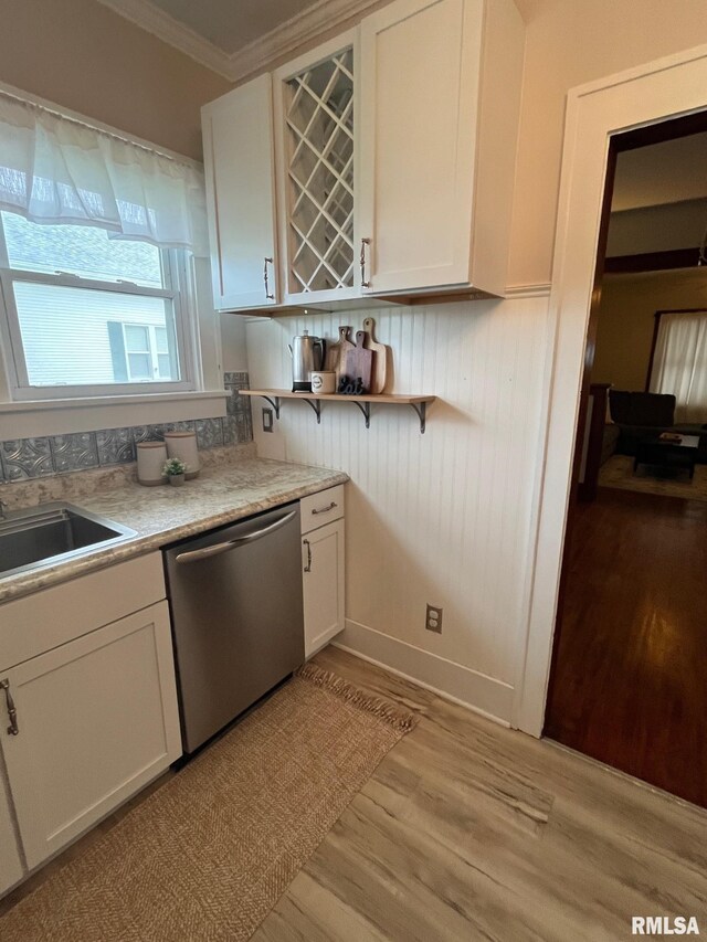 kitchen with crown molding, white cabinetry, a sink, light wood-style flooring, and dishwasher