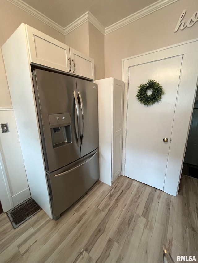 kitchen featuring white cabinets, stainless steel fridge, ornamental molding, and light wood-style floors