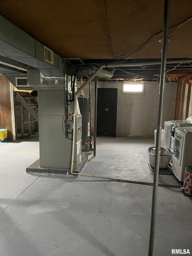basement featuring visible vents, washing machine and clothes dryer, water heater, heating unit, and stairs