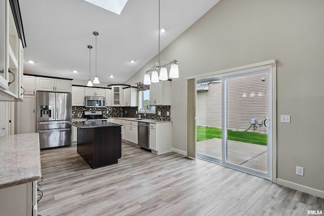 kitchen with light wood-style flooring, a center island, stainless steel appliances, backsplash, and a skylight