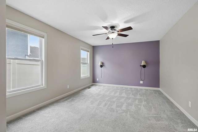 carpeted empty room with baseboards, a ceiling fan, and a wealth of natural light