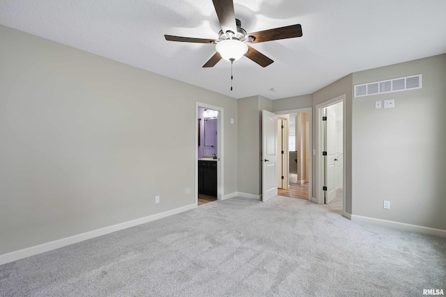 unfurnished bedroom with light colored carpet, ensuite bath, a ceiling fan, baseboards, and visible vents