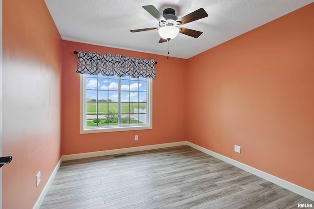 empty room with a ceiling fan, a textured ceiling, baseboards, and light wood-style floors