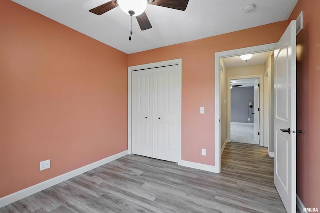 unfurnished bedroom with baseboards, ceiling fan, a closet, and wood finished floors