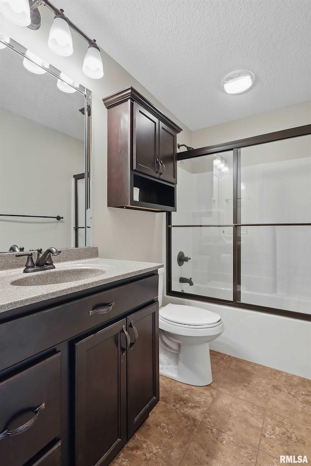 bathroom with a textured ceiling, vanity, tile patterned floors, toilet, and shower / bath combination with glass door