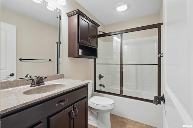 bathroom with vanity, combined bath / shower with glass door, tile patterned flooring, and toilet