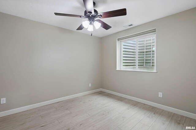 empty room with baseboards, visible vents, ceiling fan, and light wood finished floors