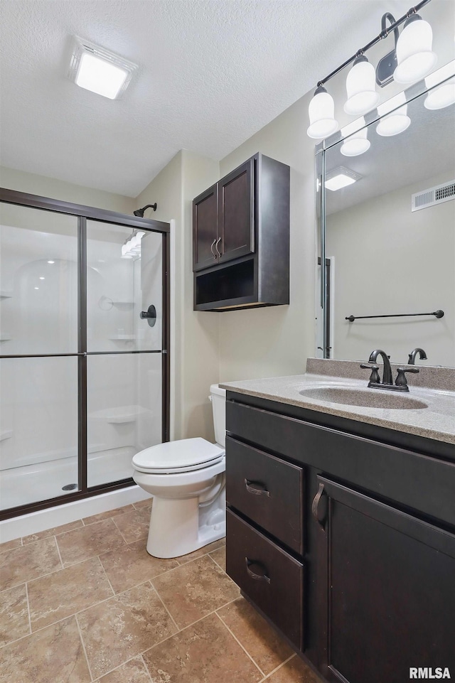 bathroom featuring a textured ceiling, visible vents, a stall shower, vanity, and toilet
