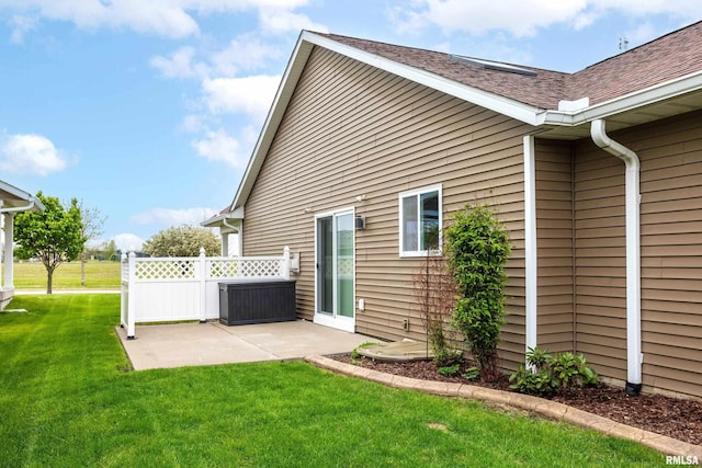 rear view of house featuring a yard, fence, a shingled roof, and a patio area