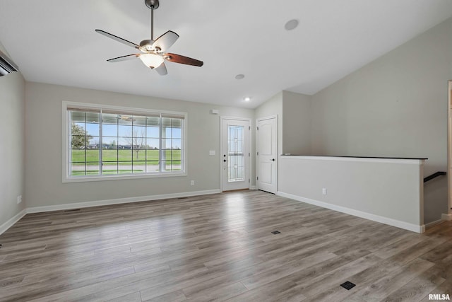 unfurnished living room with a healthy amount of sunlight, a ceiling fan, vaulted ceiling, and wood finished floors
