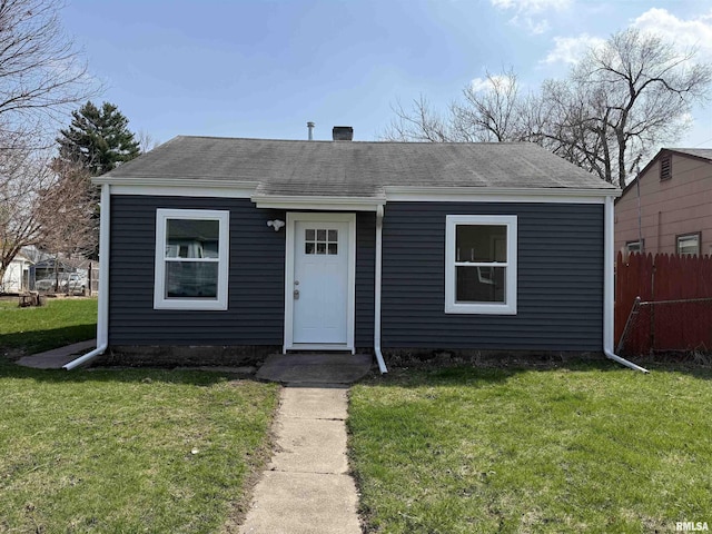 bungalow-style house featuring a shingled roof, a front lawn, and fence