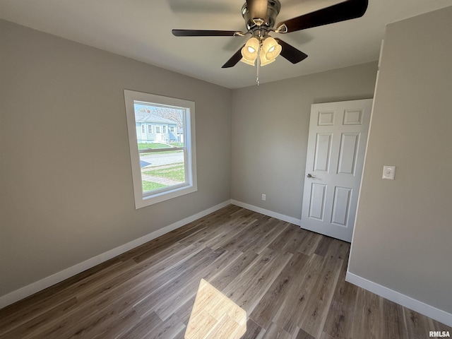 spare room with baseboards, ceiling fan, and wood finished floors