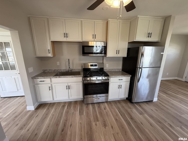 kitchen featuring ceiling fan, appliances with stainless steel finishes, light wood-type flooring, a sink, and baseboards