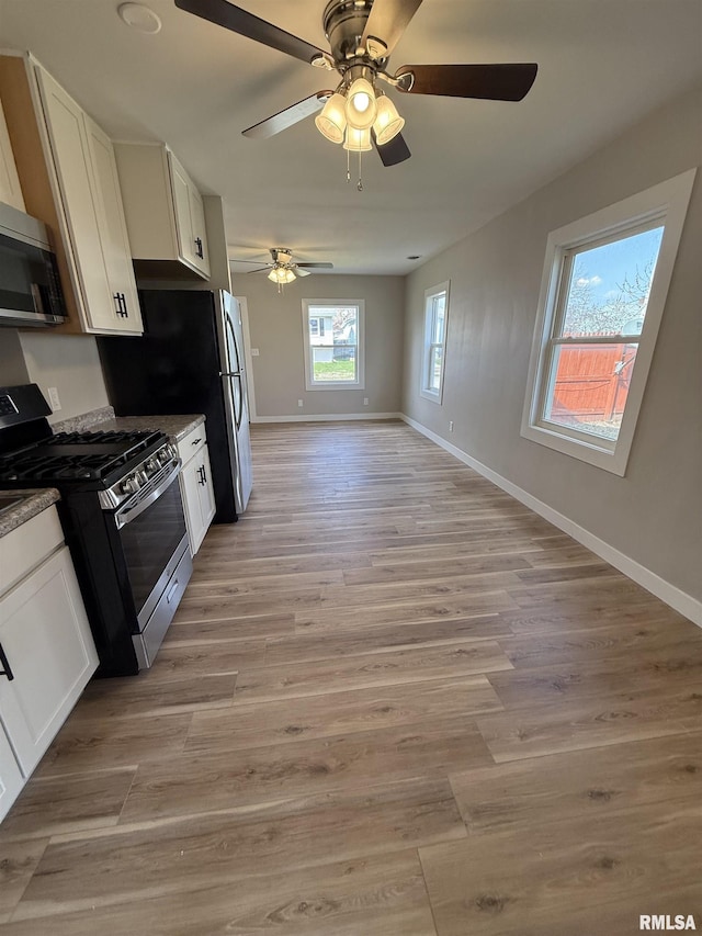 kitchen with baseboards, white cabinetry, appliances with stainless steel finishes, and light wood finished floors