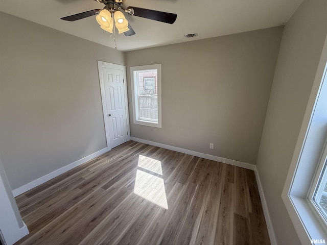 spare room with baseboards, a wealth of natural light, wood finished floors, and visible vents