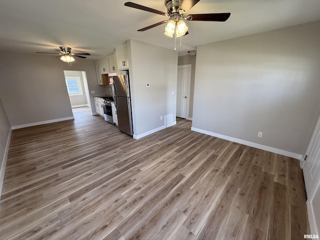 unfurnished living room with baseboards, a ceiling fan, and wood finished floors