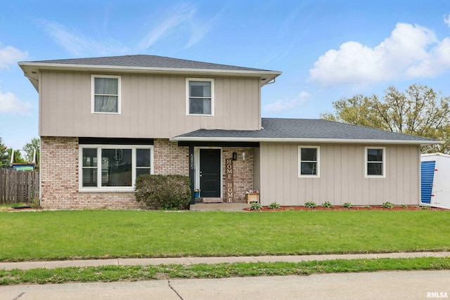 traditional-style home with fence, a front lawn, and brick siding