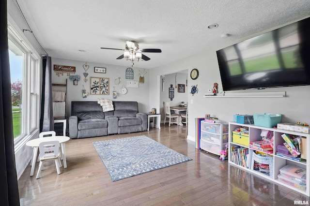 living area featuring a ceiling fan, a textured ceiling, and wood finished floors