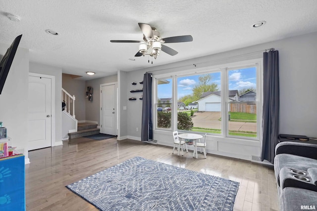 entryway featuring a textured ceiling, ceiling fan, wood finished floors, and stairway