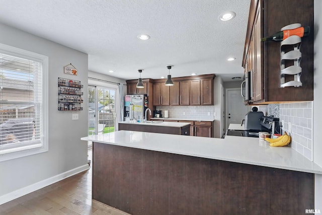 kitchen with decorative backsplash, a textured ceiling, a sink, baseboards, and stainless steel appliances