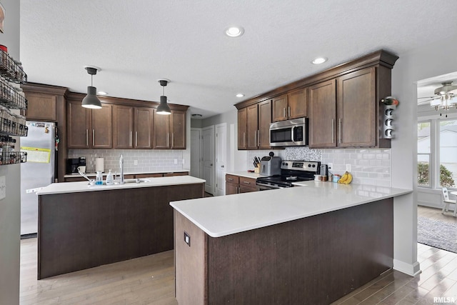 kitchen featuring decorative backsplash, light wood-type flooring, light countertops, a sink, and appliances with stainless steel finishes