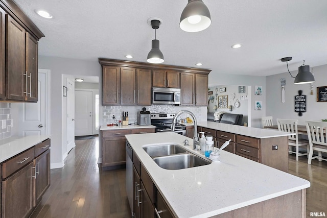 kitchen with a sink, dark wood-style flooring, appliances with stainless steel finishes, and backsplash
