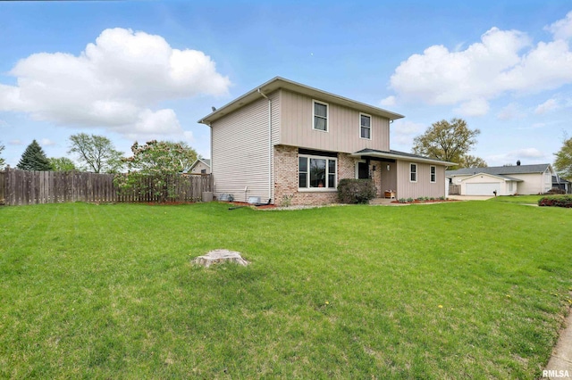 rear view of property with a yard, brick siding, and fence