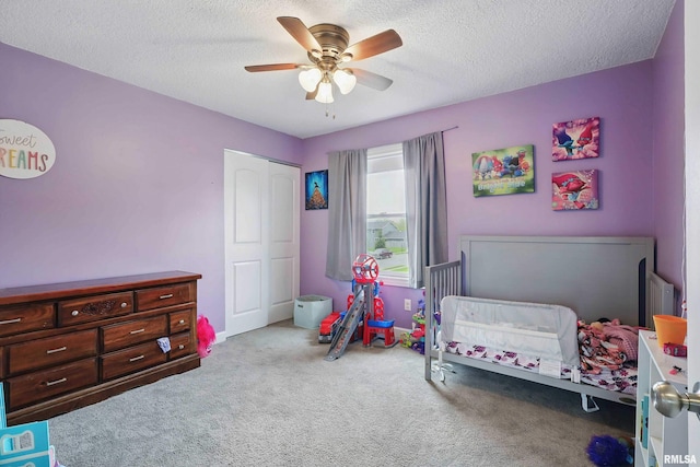 carpeted bedroom featuring a closet, a textured ceiling, and ceiling fan
